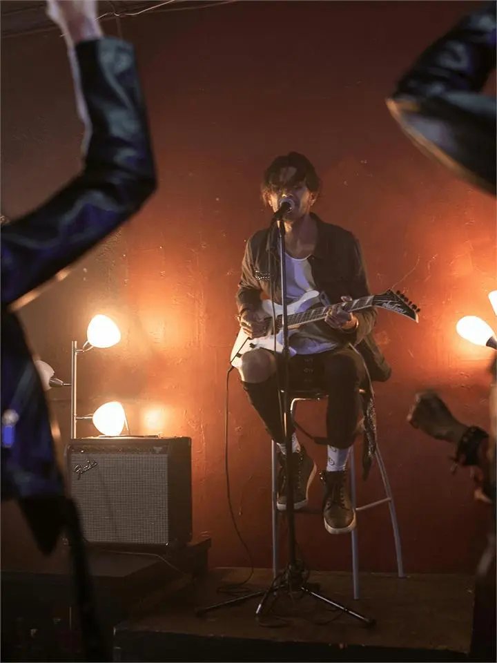 A guitarist performing on stage under warm spotlights