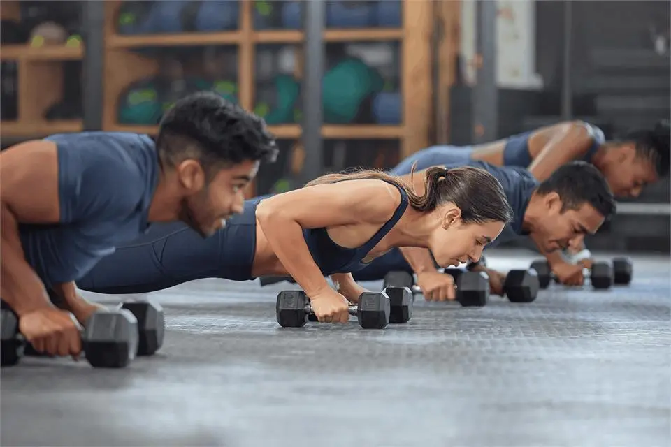 Two people doing push-ups with dumbbells in a fitness class