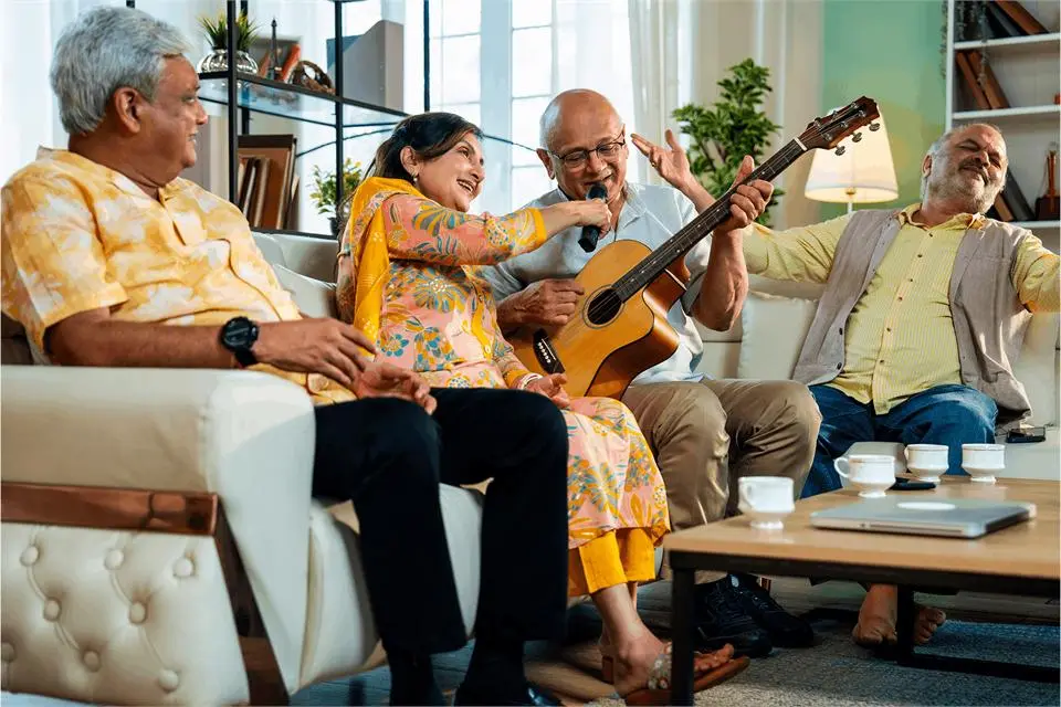 A family singing along on a sofa while a man plays acoustic guitar