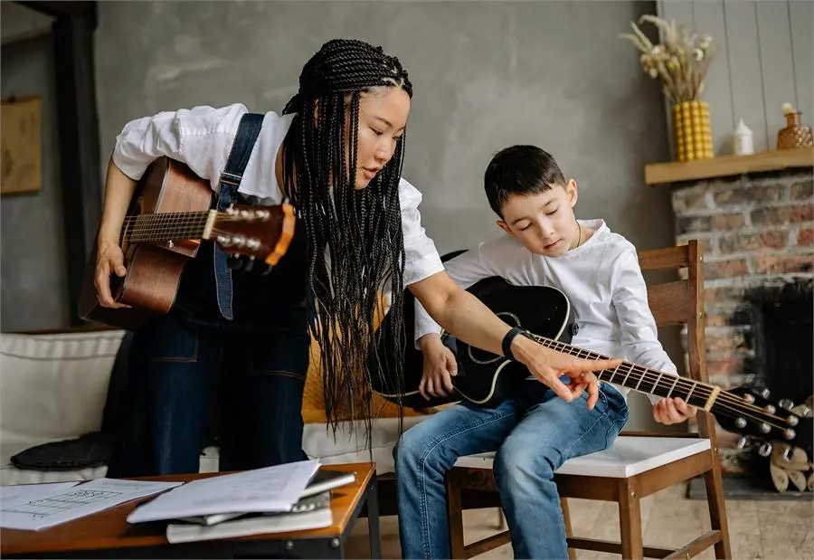 A teacher showing a young student how to play the guitar