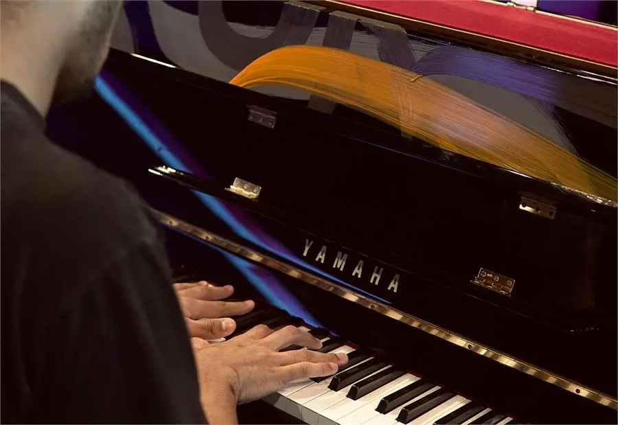 Hands playing a Yamaha upright piano